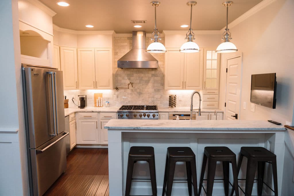 Fully equipped kitchen with white cabinetry, stainless steel appliances, and a breakfast bar with seating.