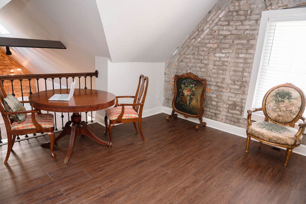 Quiet upper-level loft utilized as a workspace or reading nook, featuring natural light and exposed brick details.