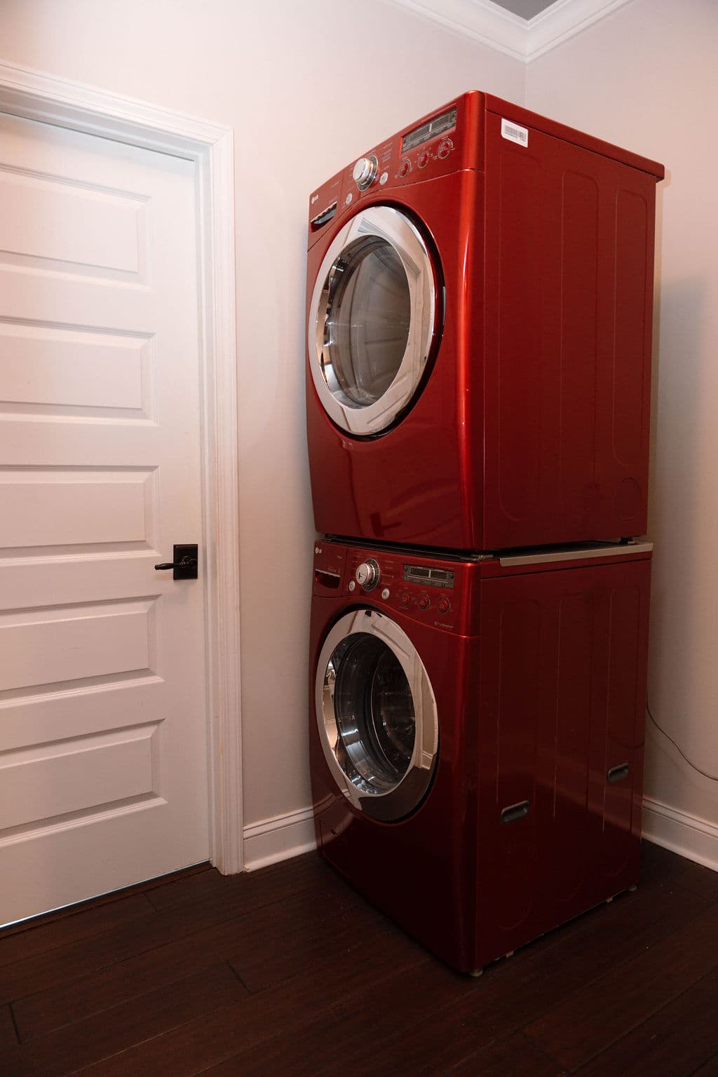 Laundry area featuring a stacked set of metallic red front-loading washer and dryer units.