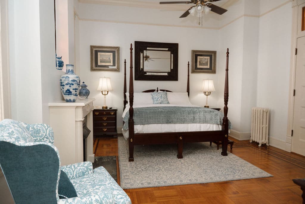 Spacious bedroom with parquet floors, fireplace, and four-poster bed.